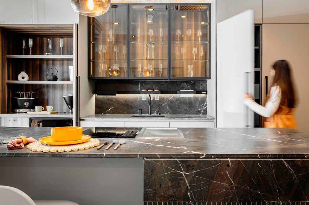 Modern kitchen featuring Goiana Quartzite countertops and backsplash, with sleek white cabinetry, black glass cabinets, and integrated lighting