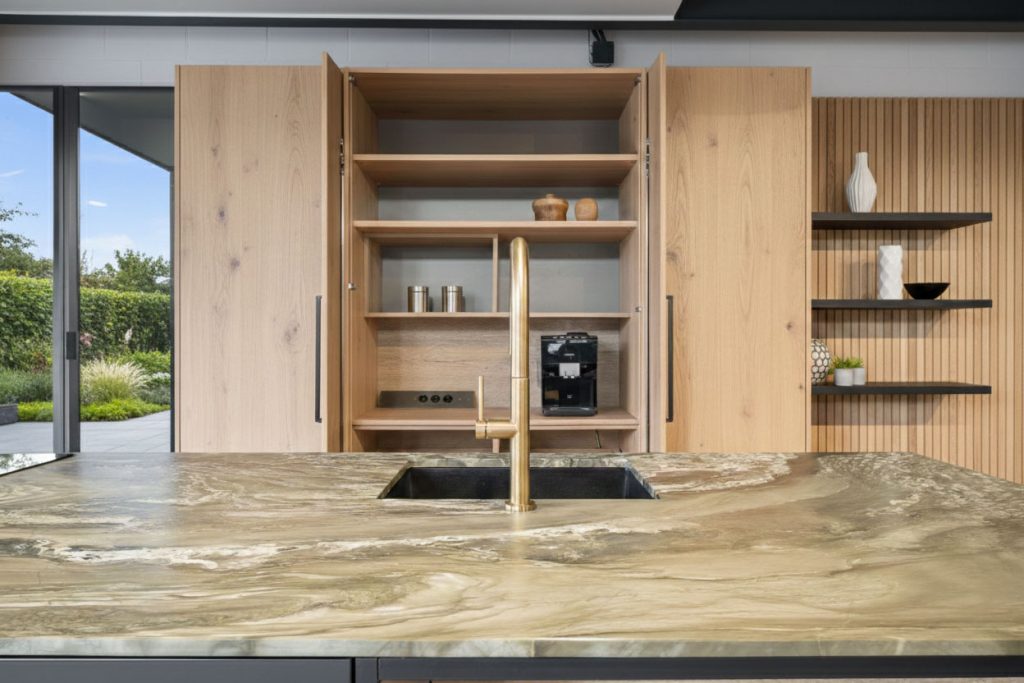 Warm brass fixtures, timber cabinetry and a TERRA® Alisia quartzite countertop come together in a harmonious and elegant kitchen design